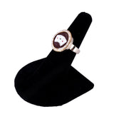 Ring with a circular design on a black stand against a white background