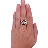Hand wearing a ring with a circular design on a white background
