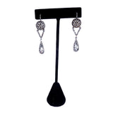 Pair of silver teardrop earrings on a black earring stand against a white background