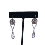Pair of silver earrings with teardrop design on a black earring stand.