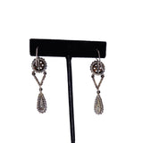 Pair of silver earrings with dangling beads on a black earring stand.