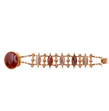 Gold bracelet with red and pink stones on a white background