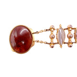 Gold bracelet with a large red stone and smaller stones on a white background
