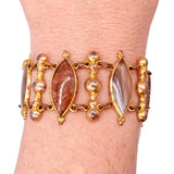 Gold bracelet with stone accents on a wrist against a white background