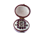 Jewelry box with a decorative brooch featuring red gemstones on a white background