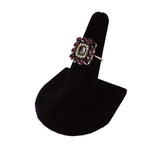 Decorative ring with gemstones on a black stand against a white background