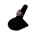 Ring with purple gemstones on a black velvet stand against a white background