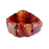 A chunky beaded stretch bracelet made of polished red and orange banded agate stone, shown on a plain white background.