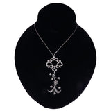 A silver-toned floral pendant necklace displayed on a black velvet jewelry bust against a white background.