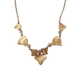 A textured gold necklace featuring irregular, organic-shaped metal pieces connected by small beads on a delicate chain, shown against a plain white background.