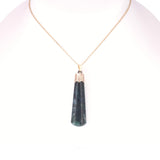 A gold chain necklace with a teardrop-shaped dark green stone pendant and a gold cap, displayed on a white mannequin bust.