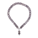A chunky silver-toned necklace made of textured, irregular stone-like beads, featuring a small hanging charm at the bottom, shown against a plain white background.